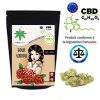 Un sachet noir décoré d’une femme brune « Sour Widow », à côté d’un tas de fleurs vert clair.