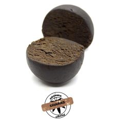 Deux morceaux de résine CBD Charas, l’un entier et l’autre coupé en deux, montrant une texture intérieure brune et compacte.