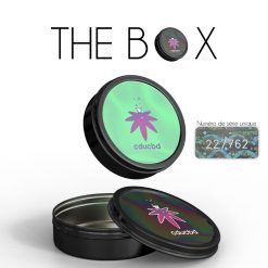 Boîte métallique ronde noire avec couvercle iridescent illustré du logo cducbd, accompagnée d’un numéro de série unique visible sur un autocollant holographique.