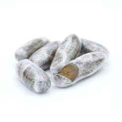 Cinq morceaux de résine de chanvre en forme d’ovale allongée, emballés dans du film transparent, dont un partiellement ouvert laissant voir la texture brune et compacte du produit à l’intérieur.