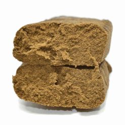 Deux morceaux de résine de chanvre de couleur brune, à la texture sèche et mousseuse, empilés l’un sur l’autre.