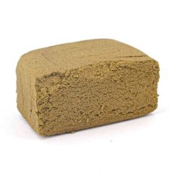 Bloc compact de résine de chanvre de couleur brun clair, à la texture mousseuse et friable, photographié sur fond blanc.