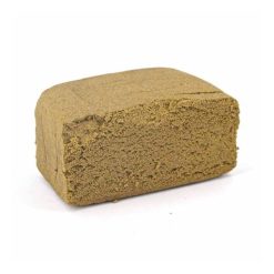 Bloc de résine de cannabis brun clair avec une texture granuleuse et friable.