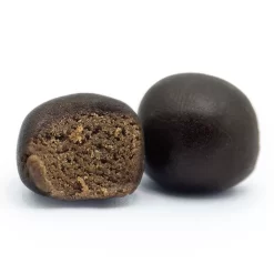 Deux boules de résine noire, l'une entière et l'autre coupée en deux, révélant une texture intérieure poreuse et brune.
